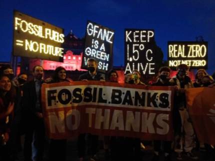 COP26 dışında eylemciler fosil yakıt finansmanını protesto eden pankartlar tutuyor.